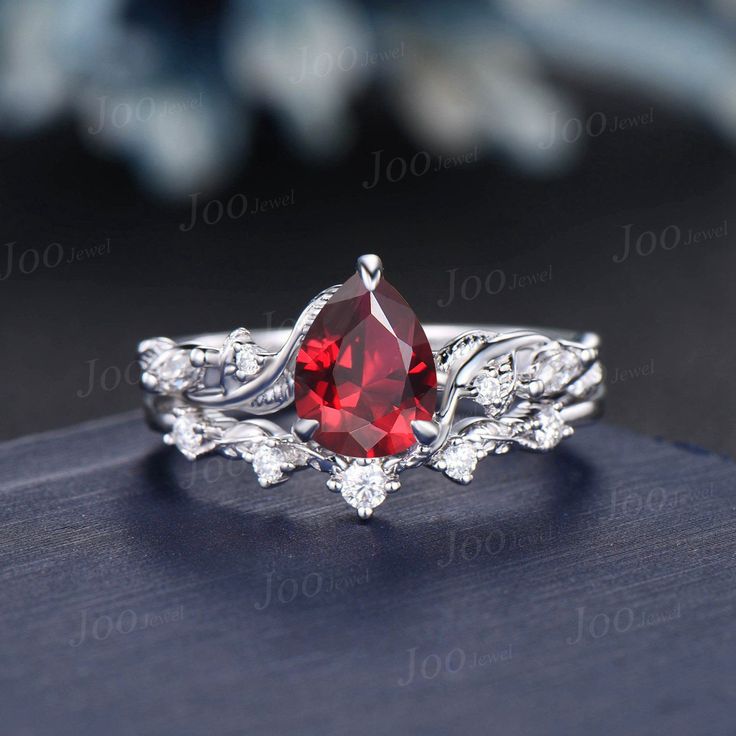 a close up view of a ring with a red stone in the center and white diamonds around it