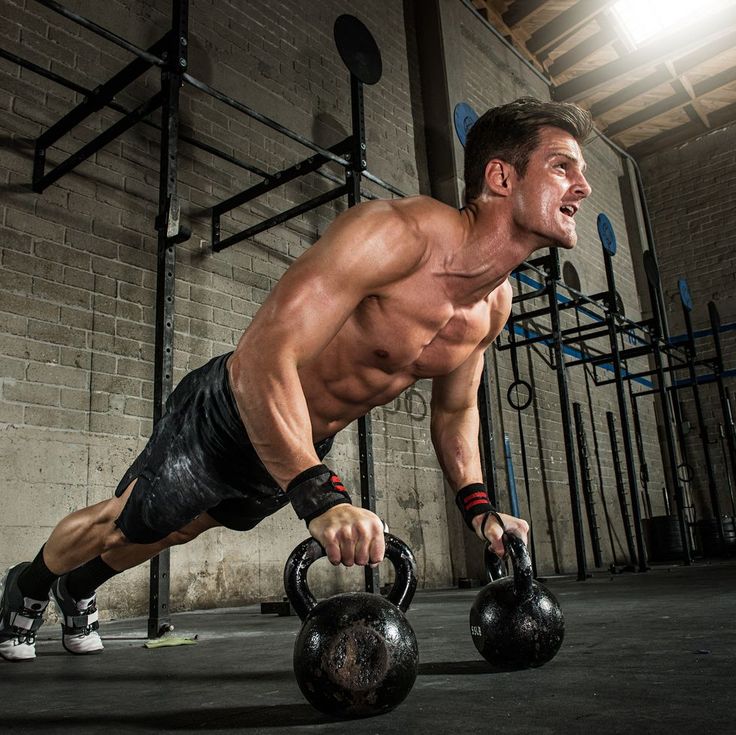 a man doing push ups with two kettles