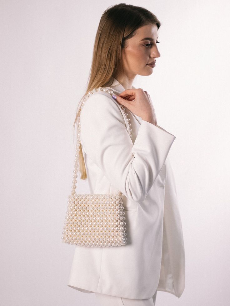 An ivory beaded bag is a versatile accessory that can be dressed up or down, making it suitable for a range of occasions, such as weddings, cocktail parties, or formal events. It can add a touch of elegance and sophistication to any outfit. The bag is roomy, fits a phone 15 cm long and many women's things. The bag is woven from fishing  line, which can withstand 25 kg. It is very reliable as it closes with a magnetic clasp. 100% handmade Material: acrylic pearl beads 8 mm & 12 mm Size:  > width Beige Evening Bag With Pearl Embroidery, Evening Clutch Shoulder Bag With Pearl Embroidery, Evening Clutch With Pearl Embroidery, Beige Evening Bag With Pearl Embroidery For Formal Occasions, Formal Beige Evening Bag With Pearl Embroidery, Handmade Pearl Shoulder Bag For Evening, Evening Shoulder Bag With Pearl Embroidery, Rectangular Shoulder Bag With Pearl Embroidery For Evening, Evening Rectangular Shoulder Bag With Pearl Embroidery