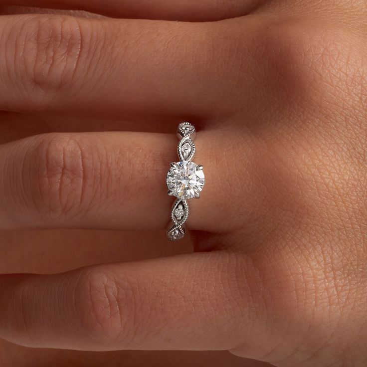 a woman's hand with a diamond engagement ring on her left hand, and an oval shaped diamond in the middle