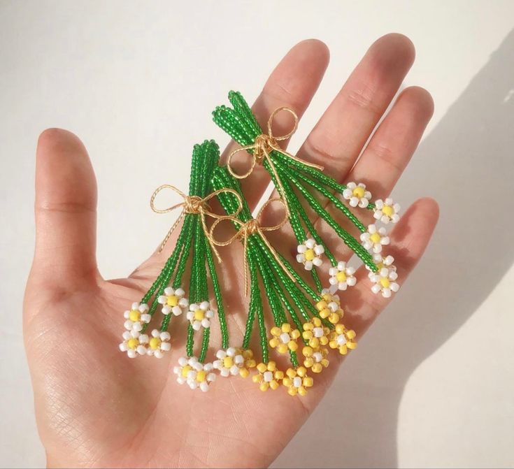 a hand is holding some beads in the shape of pineapples and daisies