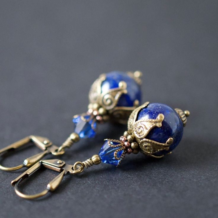 These Victorian Lapis Earrings come in a vibrant, and vivid deep dark blue hues.    These natural lapis gemstones are set in layers of ornate antique gold brass plated bead caps and beads, and topped in finest quality European sapphire dark blue crystals.   Quality handcrafted lapis lazuli jewelry for you to wear everyday, or great bridal earrings for the Victorian Wedding.   Treat yourself, or someone special! Ideal gift for the women in your life! . . . ♥  Earrings Length : 1 1/2 inches  ♥  Lapis Lazuli Gemstones : smooth round (12mm) ♥  Finest Quality Crystals : sapphire blue bicone shaped (6mm)  . . . ♥  Shown from antique gold brass plated fancy shield style lever back ear wires ♥  Select your ear wires from the drop down menu. ♥  The fancy lever backs feature a shield on the front ba Dark Blue Crystals, Crystal Birthday, Ornate Jewelry, Lapis Jewelry, Artisan Jewelry Handmade, Lapis Earrings, Lapis Lazuli Jewelry, Lapis Lazuli Necklace, Birthday Gift For Women