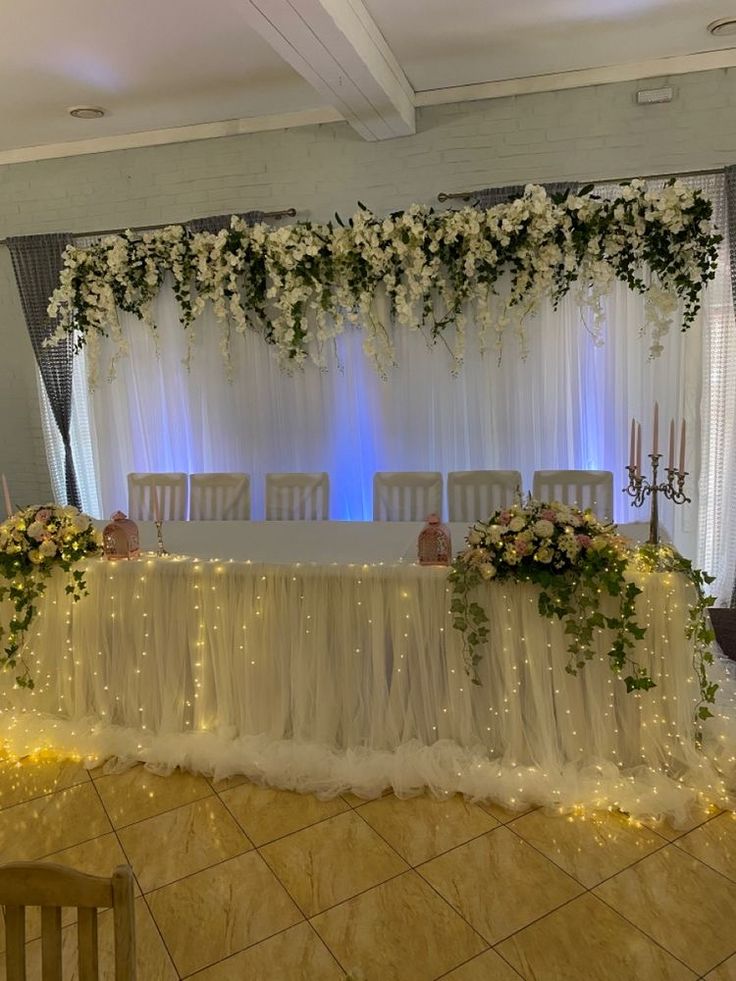 the table is set up with white flowers and greenery for an elegant wedding reception