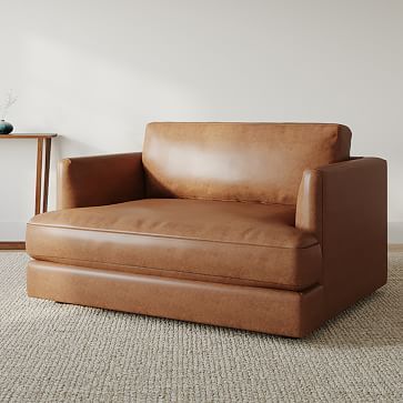 a brown leather chair sitting on top of a carpeted floor