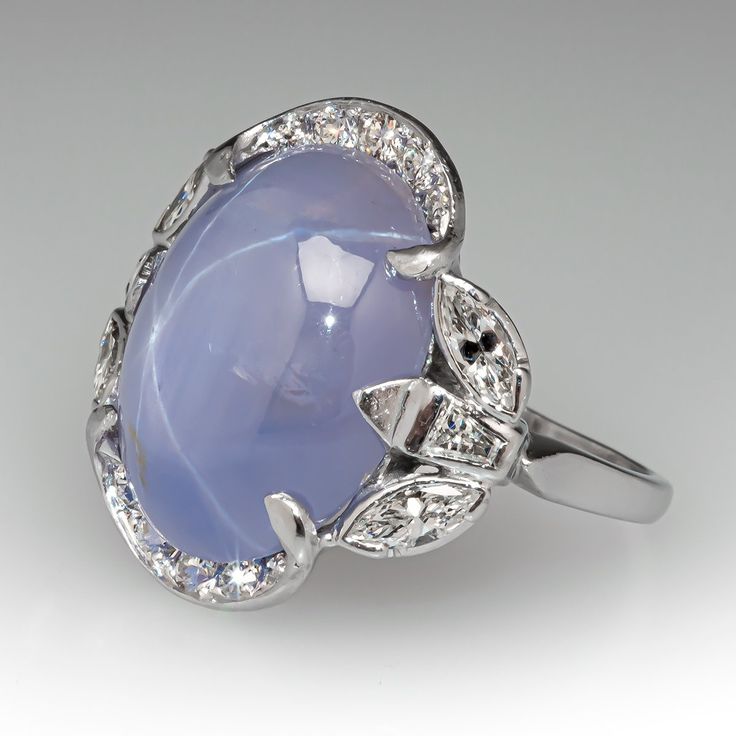 This stunning vintage ring is centered with an oval cabochon cut natural star sapphire set into a six-prong setting. The sapphire is bordered with ten (10), bead set, round brilliant cut diamonds, four (4), semi-bezel set, marquise brilliant cut diamonds and two (2), bezel set, tapered baguette cut diamonds. The ring measures 19.6mm at the top, rises 6.5mm above the finger, tapering to 1.4mm wide and 0.9mm thick at the base of the shank. It is currently a size 6. Luxury Domed Sapphire Ring Fine Jewelry, Luxury Cabochon Sapphire Wedding Ring, Luxury Heirloom Sapphire Open Ring, Fine Jewelry In Platinum With Cabochon, Fine Jewelry White Gold Cabochons For Anniversary, Fine Jewelry Platinum Cabochon, White Gold Fine Jewelry Cabochons For Anniversary, Fine Jewelry Diamond Cabochons For Wedding, Vintage Oval Cabochon Gemstones