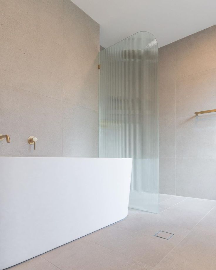 an empty bathroom with a white counter and gold faucet on the wall next to it