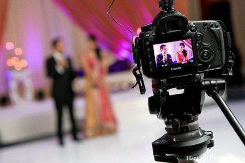 a video camera on a tripod in front of a wedding couple at the reception