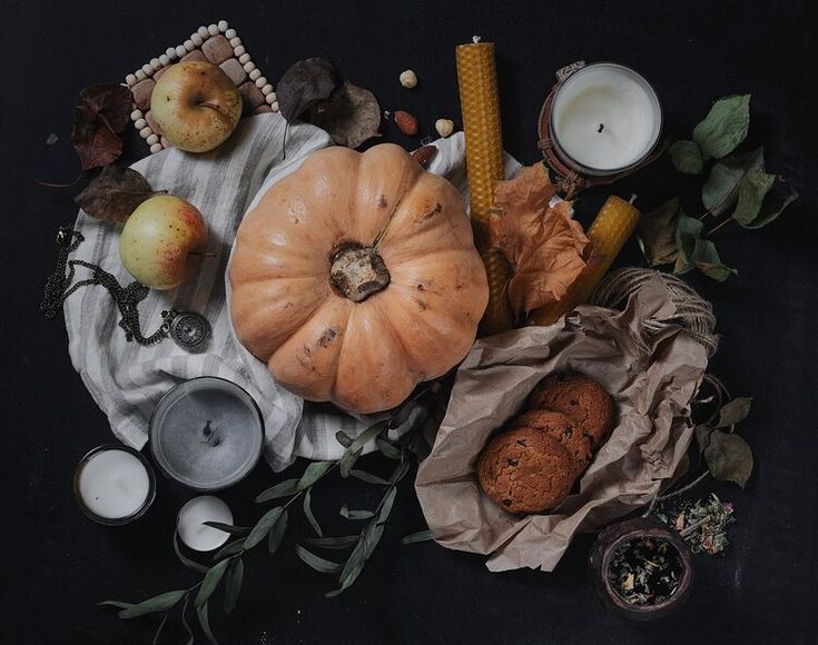 an assortment of food and candles on a black tablecloth with leaves, pumpkins, corn