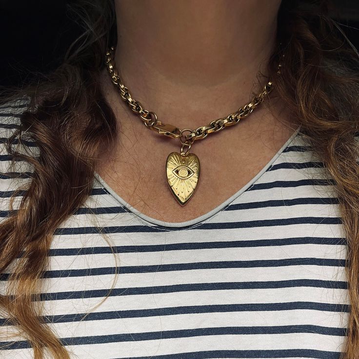 "Our Evil Eye Heart Necklace is just the thing your jewelry collection needs. Featuring a large heart this gold chunky necklace will make your outlook unforgettable. ★ Complete the look ★ Matching Bracelet Available to Purchase Here: https://yourockjewels.etsy.com/listing/1667852952/heart-charm-bracelet-chunky-gold-chain ---------------------------------------- M A T E R I A L S * 18K gold-plated stainless steel link chain 8mm. * Water-resistant, Tarnish resistant, Hypoallergenic * 24Κ gold-plated over copper heart pendant 25x39mm * Stainless steel clasp to secure perfectly.  * Different Chain lengths, from 16\" to 20\" inches long including the clasp. Choose the length from the dropdown menu.  * Chain will not come with an extension. ♥ YOUROCK JEWELS TIP ♥: Wear it alone or mix other chai Metal Heart Necklace With Chunky Chain, Gold-tone Heart Chain Necklace, Gold-tone Heart Charm Chain Necklace, Gold Metal Heart Choker Necklace, Gold Heart Pendant Chain Necklace, Gold Heart Necklace With Chunky Chain For Gift, Gold Heart Necklace With Chunky Chain, Gold Chunky Heart-shaped Jewelry, Chunky Heart-shaped Gold Jewelry