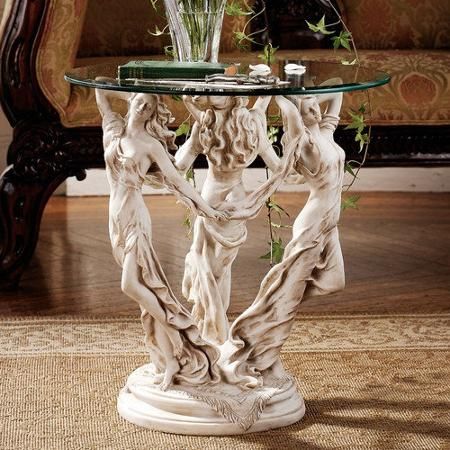 a glass topped table with statues on it in front of a couch and coffee table