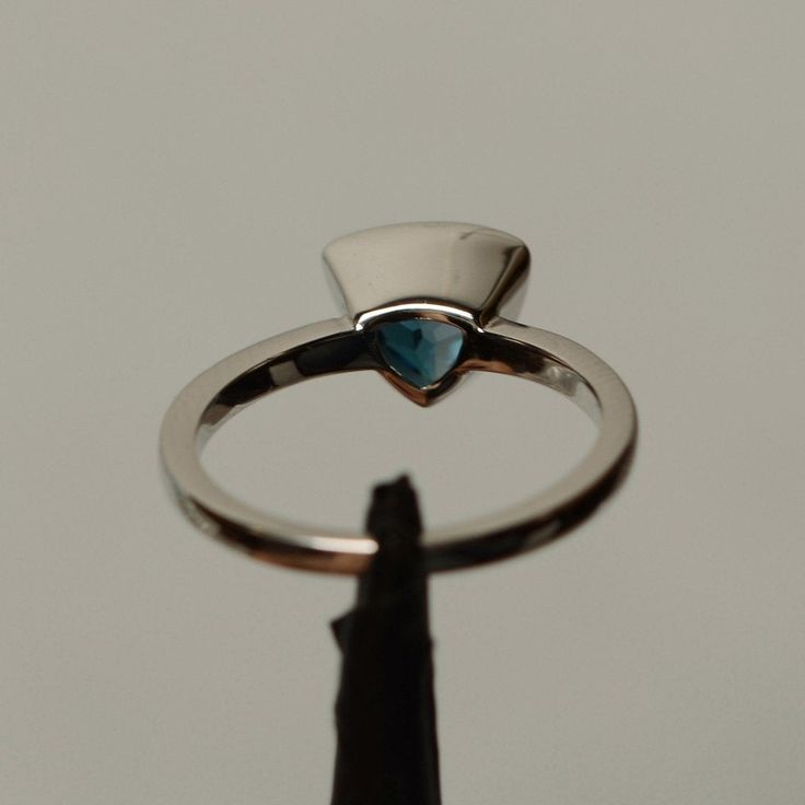 It is a real London blue topaz ring. The main stone is 8 mm*8mm triangular. The basic metal is sterling silver and plated with rhodium. To change the metal to a solid gold (white/rose) or platinum is also available, please ask for a quotation if you want. You can also go to my shop Home for more elegant rings: https://www.etsy.com/shop/godjewelry?ref=hdr_shop_menu Topaz is November birthstone. More topaz rings: https://www.etsy.com/shop/godjewelry?ref=hdr_shop_menu&section_id=20715039 Custom Trillion Cut Sapphire Anniversary Ring, Blue Topaz Ring With Bezel Setting For Promise, Modern White Gold Trillion Cut Ring, Modern Silver Trillion Cut Ring, Silver Sapphire Trillion Cut Promise Ring, Silver Trillion Cut Sapphire Promise Ring, Blue Trillion Cut Sterling Silver Ring, Modern Blue Topaz Jewelry With Bezel Setting, Modern Trillion Cut Promise Ring