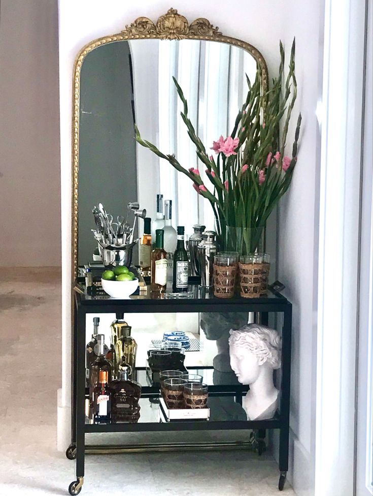 a mirror sitting on top of a shelf filled with bottles and vases next to a busturine