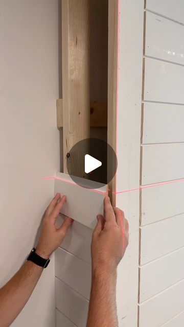 a man is working on the wall with pink tape