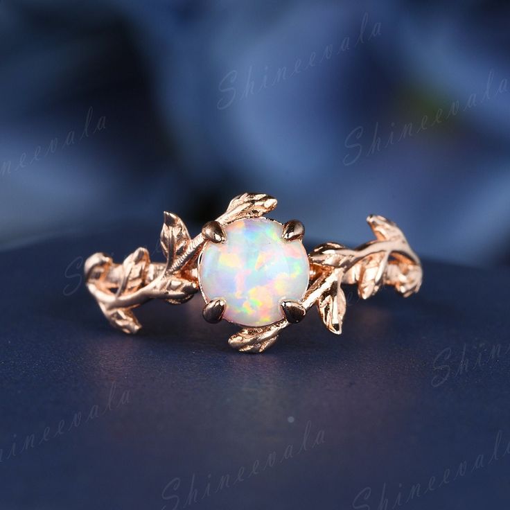 a gold ring with an opal in the center and leaves on it's sides