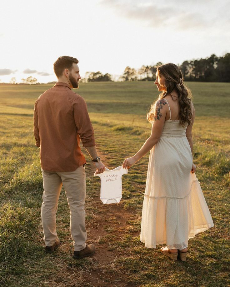 a man and woman holding hands while standing in a field