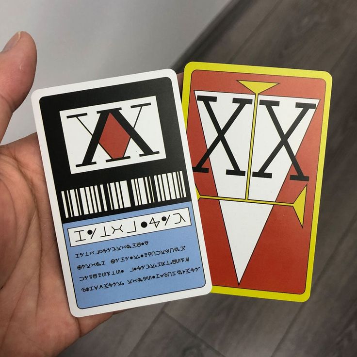 a hand holding two playing cards in front of the camera, both with barcodes on them