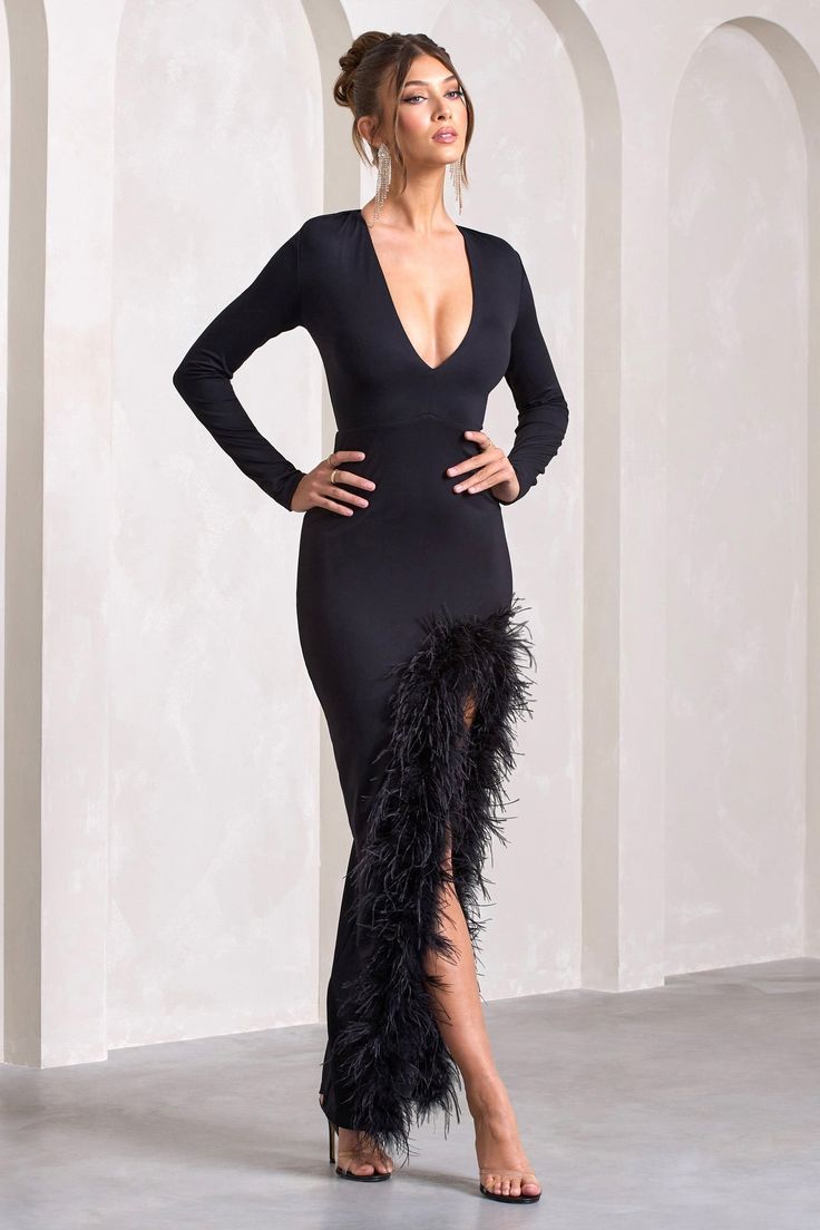 a woman in a black dress with feathers on the side and her hands on her hips