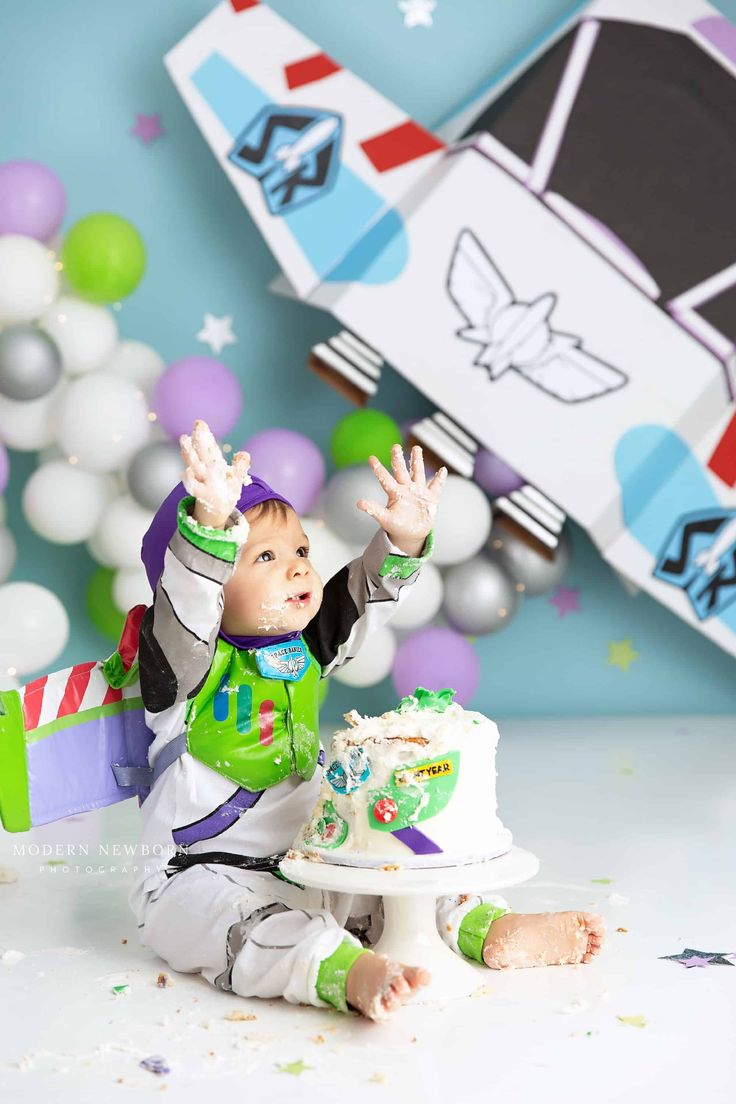 a baby boy sitting in front of a cake