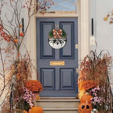 the front door is decorated with pumpkins and flowers