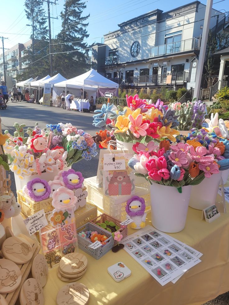 a table with flowers and other items on it at an outdoor market place in the city