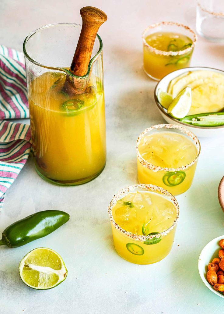 three glasses filled with drinks sitting on top of a table next to plates of food