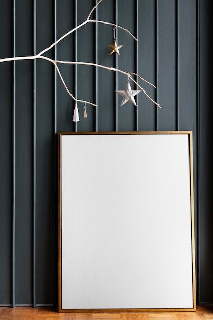 an empty frame on the floor next to a christmas tree branch with ornaments hanging from it