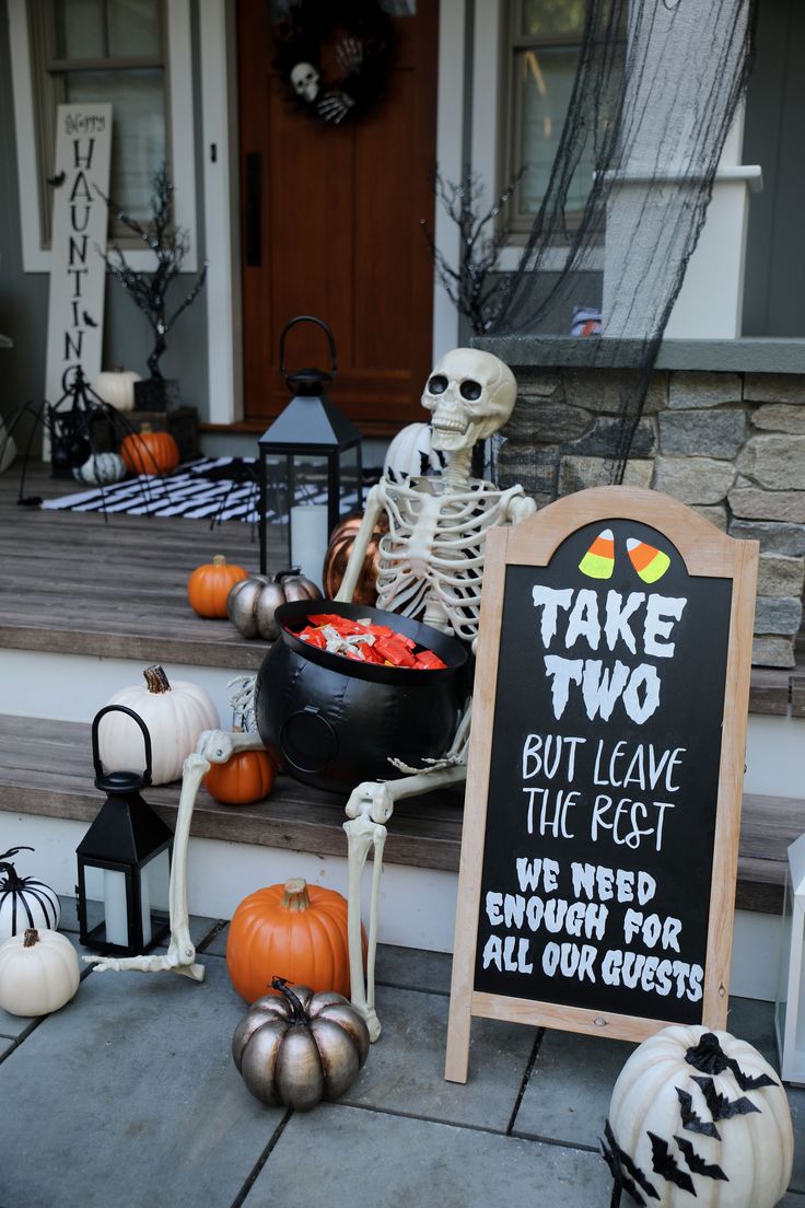 halloween decorations on the front steps of a house with a chalkboard sign that says take two but leave the feast we need crunch for all our guests