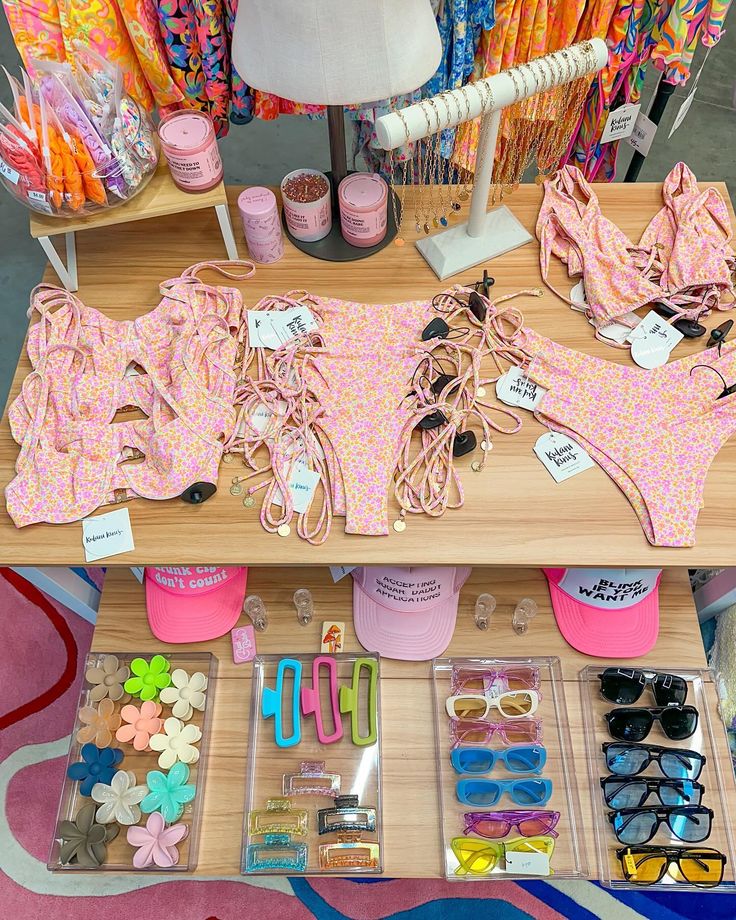 an assortment of bikinis and accessories on display at a clothing store, including sunglasses