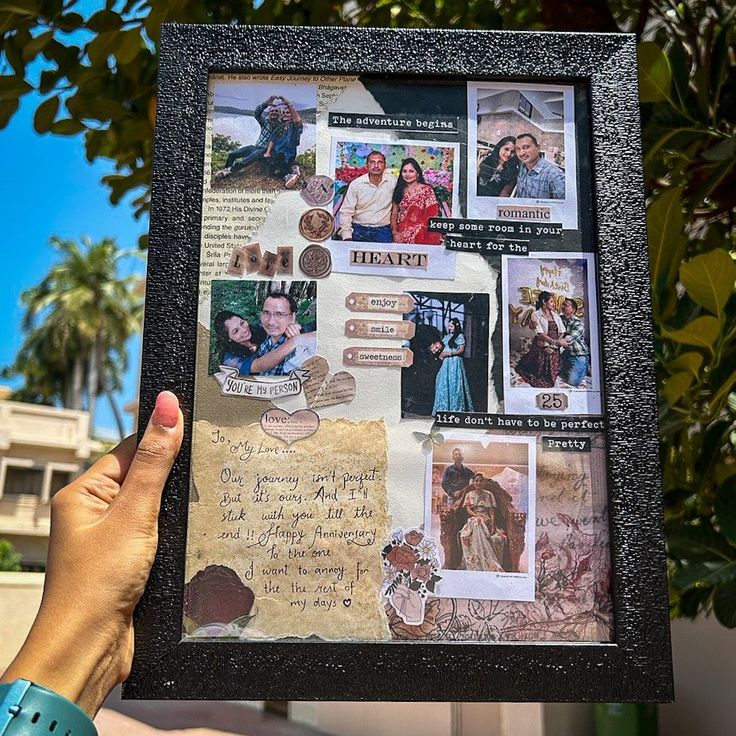 a person holding up a framed collage with pictures and letters on it in front of some trees