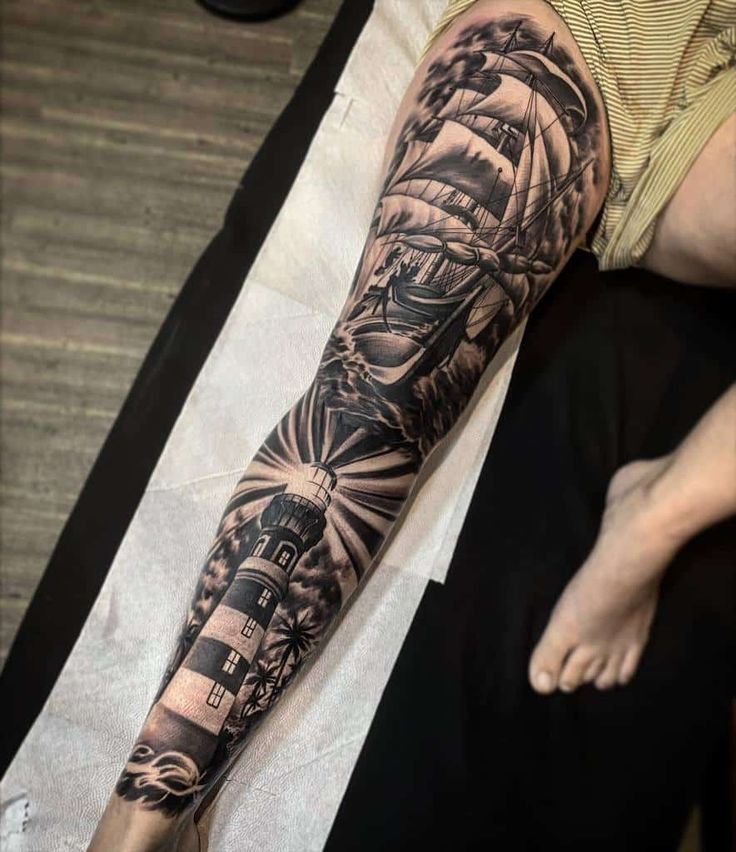 a man's arm with a ship and lighthouse tattoo on it