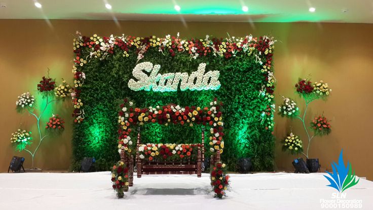 the backdrop is made up of flowers and greenery, along with a bench for seating