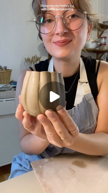 a woman wearing glasses is holding a clay bowl in her hands and smiling at the camera