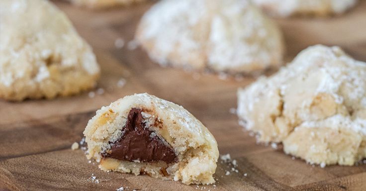 several cookies are cut in half and placed on a cutting board with powdered sugar