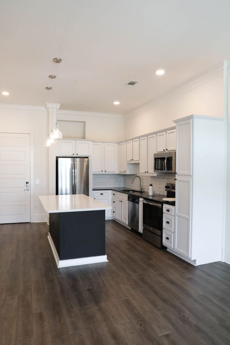 an empty kitchen with white cabinets and black counter tops