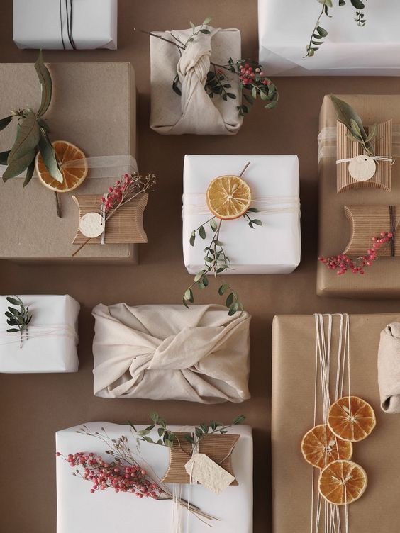 presents wrapped in brown paper with orange slices and greenery tied around them, sitting next to each other