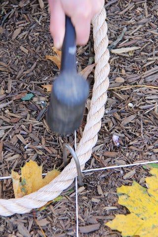 a person holding a rope with a tool in their hand and pulling it through the ground