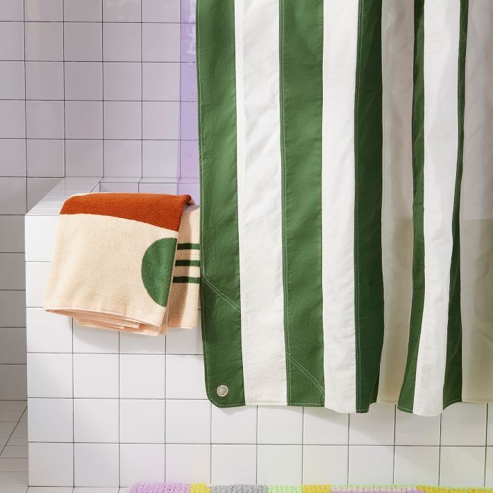 a green and white striped shower curtain next to a tiled wall