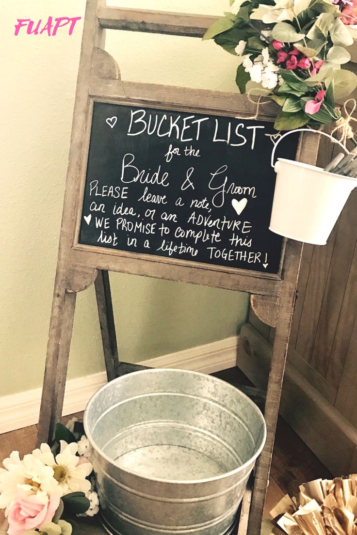 a bucket list sign sitting on top of a wooden stand next to a metal pail