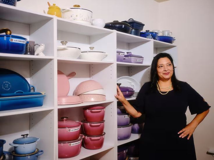 a woman standing in front of shelves filled with pots and pans