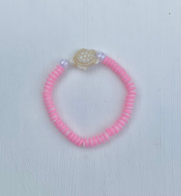 a pink beaded bracelet with a small turtle on it's end and a shell in the middle