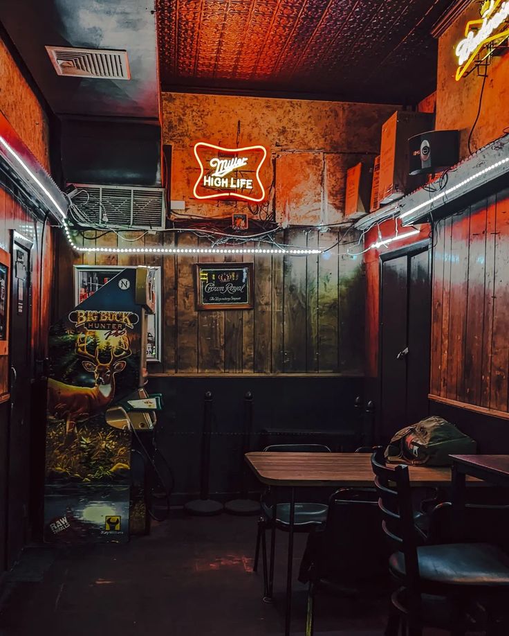 the inside of a restaurant with wooden walls and dark wood tables, chairs, and neon signs