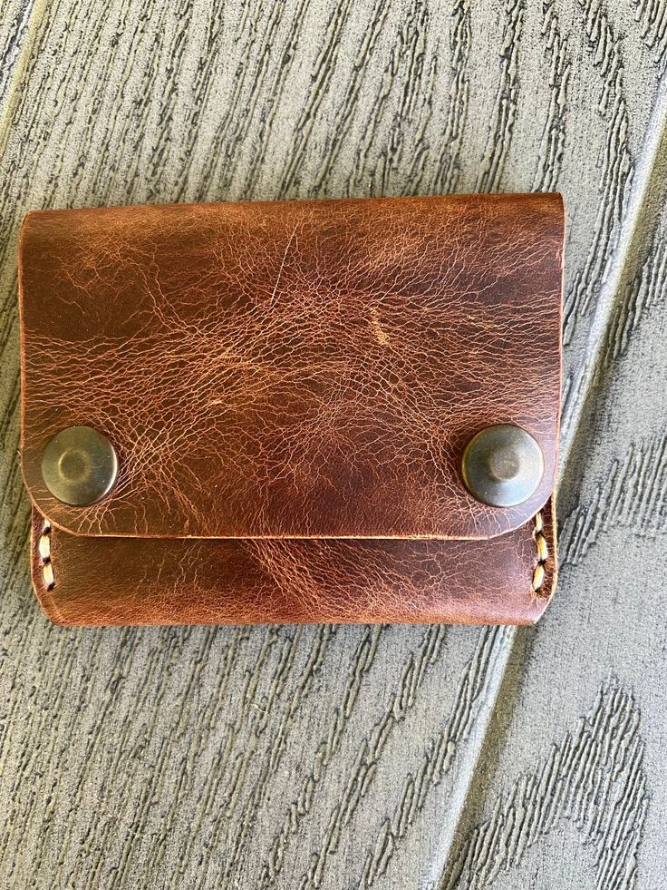 This handmade leather wallet offers three inner pockets with a snap closure.  Measurements: 102 mm X 80 mm when snapped 102 mm X 149 mm when open -- [ CARE INSTRUCTIONS ] -- * Remove dust and dirt with a soft brush or cloth. * Refrain from using detergents or chemicals. Use a damp cloth to wipe your wallet lightly and allow to air dry. * Allow them to dry naturally and never under an artificial heat source. * If the leather gets too dry, apply a neutral leather cream or conditioner on the wallet to moisturize the leather. *Please note colors may vary slightly. We try to capture the colors the best we can.* If you have any questions, please do not hesitate to contact me. Handmade Brown Wallet For Everyday Carry, Artisan Trifold Wallet With Card Slots For Daily Use, Rustic Leather Wallets With Card Slots, Brown Rectangular Trifold Wallet With Waxed Finish, Rustic Brown Wallets With Card Slots, Brown Waxed Finish Trifold Wallet, Brown Artisan Wallet With Coin Pocket, Artisan Brown Wallets With Coin Pocket, Vintage Brown Trifold Wallet For Everyday Carry