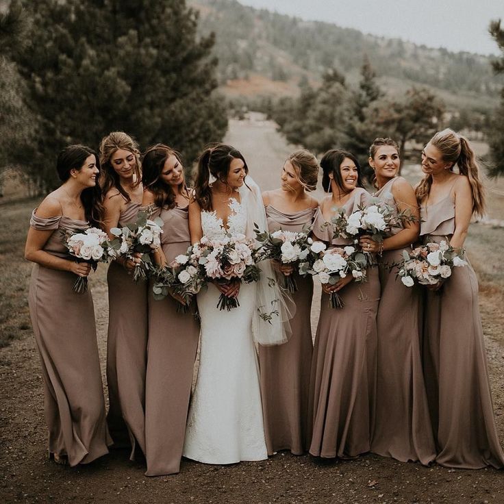 a group of women standing next to each other holding bouquets in their hands and smiling at the camera