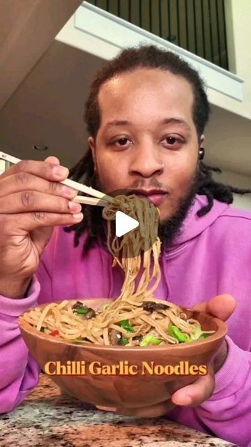 a man is eating noodles with chopsticks in his hand and the caption reads chilli garlic noodles