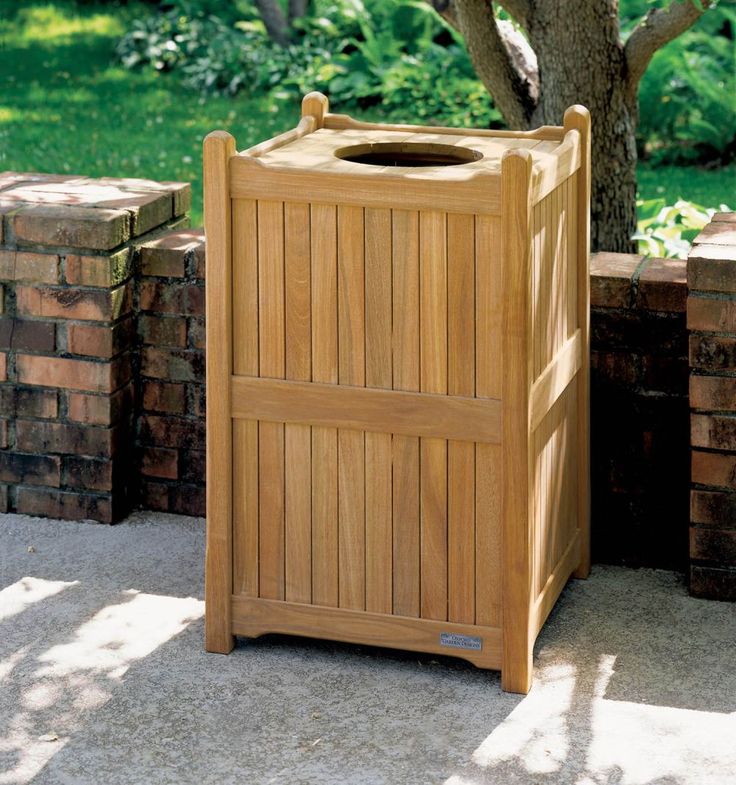 a wooden trash can sitting next to a tree