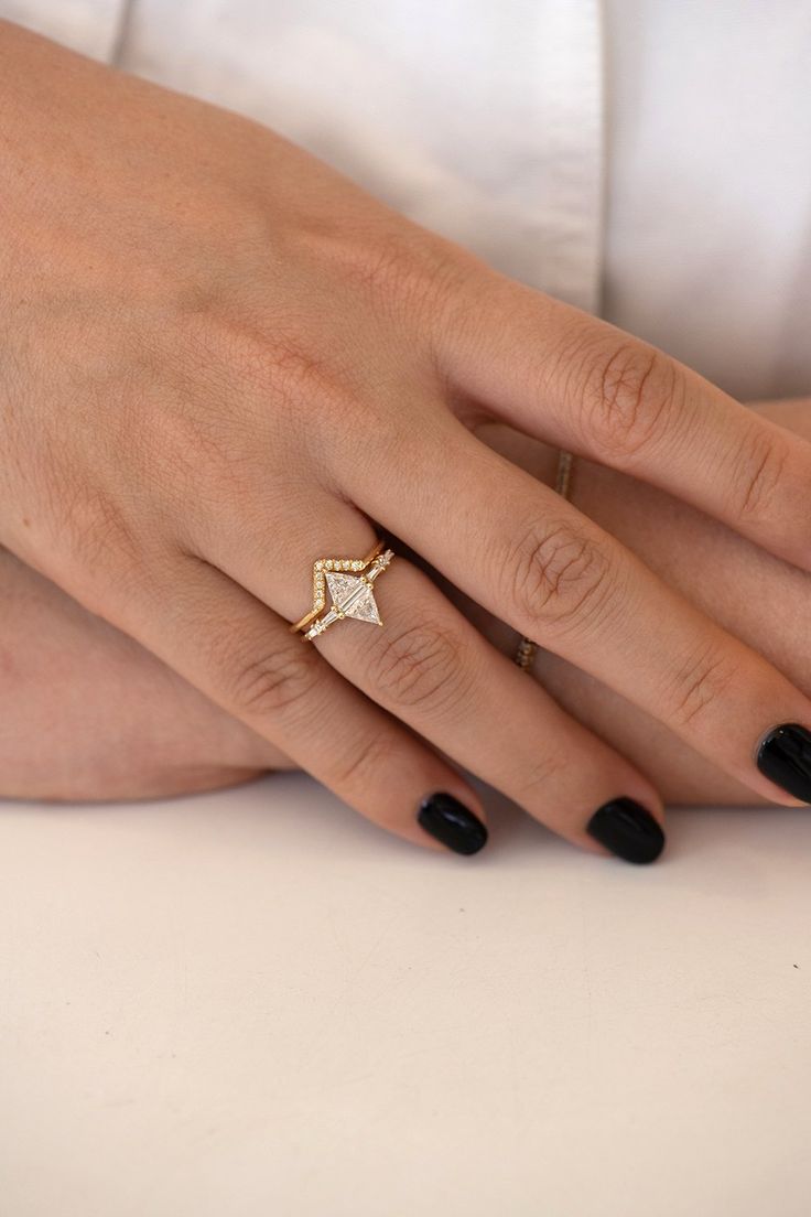 a woman's hand with black nail polish and gold ring