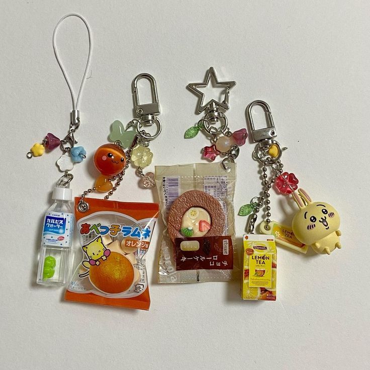 several keychains with various items attached to them on a white surface, including an orange bag