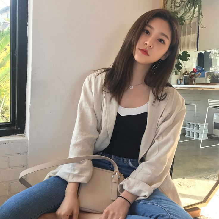 a woman is sitting on a chair holding a handbag and posing for the camera