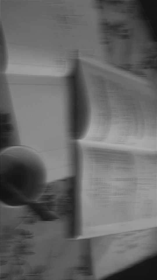 blurry photograph of stacks of newspapers in black and white photo with focus on the pages