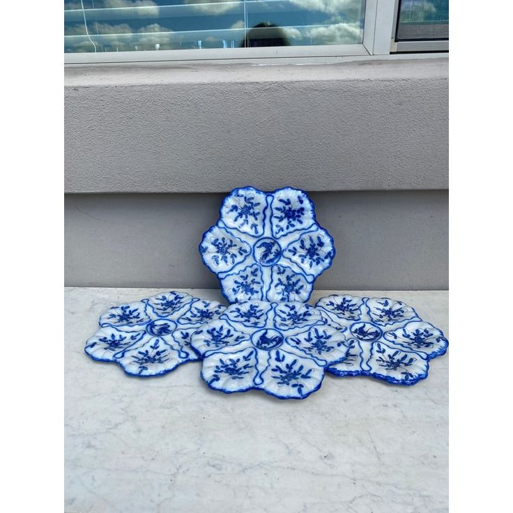 a blue and white plate sitting on top of a counter next to a window sill